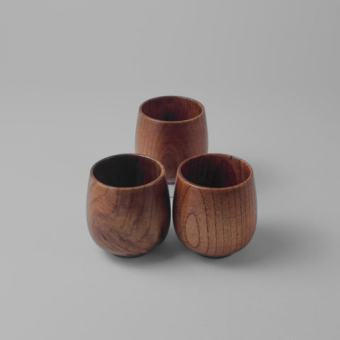 Three wooden cups on a gray surface with a light gray background